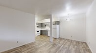 Located at 3802 N Flowing Wells Rd in Tucson, Arizona, this single-floor unit offers a clean, functional layout designed for comfortable everyday living. The open-concept living and dining area is finished with durable wood-look plank flooring and neutral white walls, creating a bright and versatile space. A pendant light fixture adds a subtle decorative touch overhead.

The kitchen is directly accessible from the living area and is well-appointed with gray cabinetry extending to the upper walls for ample storage, white laminate countertops, a double-basin stainless steel sink, and white appliances including a range, dishwasher, and refrigerator. The wood-look flooring continues seamlessly throughout this space.

The bedroom is a generously sized, quiet retreat featuring soft gray carpeting, a window with vertical blinds that allows natural light, a wall-mounted HVAC unit for individual climate control, and a sliding-door closet with a built-in shelf and hanging rod.

The bathroom is straightforward and clean, featuring a full-size tub and shower combination with white tile surround and chrome fixtures, complemented by neutral tiling underfoot. Overall, the unit presents a tidy, move-in-ready environment with a practical and cohesive aesthetic throughout.