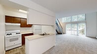Located at 2440 Fox Run Rd SW in Wyoming, Michigan, this two-story residence is thoughtfully divided across two equally sized floors. The main level opens to a combined kitchen and living area, where the kitchen features warm wood cabinetry, light countertops, a stainless steel sink, and wood-look flooring. A peninsula with an overhead cabinet separates the kitchen from the carpeted living area, which is bathed in natural light from large sliding glass doors that overlook the surrounding greenery. A staircase with a metal railing connects the floors with easy access. A half bathroom on the main level includes a wood-vanity with a single sink, a wall mirror, and wood-look flooring. The upper level offers carpeted rooms with a vaulted ceiling accented by an exposed wood beam, lending a warm architectural character. Natural light filters in through windows with views of the outdoors. Baseboard heating runs along the walls on both floors, ensuring year-round comfort. The upper-level full bathroom is outfitted with a tub-shower combination, a wood-vanity, and wood-look tile flooring. Recessed lighting and neutral tones throughout create a clean, functional, and inviting atmosphere across the entire space.