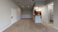 This single-floor residence at 1460 Oakcrest Dr in Columbia, South Carolina offers a thoughtfully designed layout with a seamless flow between living and dining areas. The spacious living room features vaulted ceilings, plush wall-to-wall carpeting, a ceiling fan, and large windows alongside a glass door that invite generous natural light and outdoor views. Recessed lighting adds a modern touch throughout. The kitchen is well-equipped and opens to the living space via a breakfast bar counter, showcasing rich cherry wood cabinetry, granite-style laminate countertops, and a full suite of black appliances including a range, over-the-range microwave, and dishwasher. Wood-look flooring in the kitchen provides a clean contrast to the carpeted living areas. The bedrooms continue the vaulted ceiling design, offering an airy feel with neutral gray walls, plush carpeting, ceiling fans, and windows that bring in natural light. The bathroom features a generously sized soaking tub and shower combination with white tile surround and chrome fixtures, providing a clean and functional retreat. Overall, the home presents a comfortable and practical living environment with consistent neutral tones and well-maintained finishes throughout.