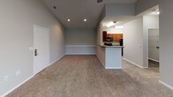This single-floor residence at 1460 Oakcrest Dr in Columbia, South Carolina offers a thoughtfully designed layout with a seamless flow between living and dining areas. The spacious living room features vaulted ceilings, plush wall-to-wall carpeting, a ceiling fan, and large windows alongside a glass door that invite generous natural light and outdoor views. Recessed lighting adds a modern touch throughout. The kitchen is well-equipped and opens to the living space via a breakfast bar counter, showcasing rich cherry wood cabinetry, granite-style laminate countertops, and a full suite of black appliances including a range, over-the-range microwave, and dishwasher. Wood-look flooring in the kitchen provides a clean contrast to the carpeted living areas. The bedrooms continue the vaulted ceiling design, offering an airy feel with neutral gray walls, plush carpeting, ceiling fans, and windows that bring in natural light. The bathroom features a generously sized soaking tub and shower combination with white tile surround and chrome fixtures, providing a clean and functional retreat. Overall, the home presents a comfortable and practical living environment with consistent neutral tones and well-maintained finishes throughout.