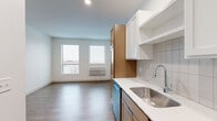 Located at 7570 32nd St N in Oakdale, Minnesota, this efficiently designed one-bedroom, one-bathroom unit offers a thoughtfully organized single-floor layout. The open-concept living and kitchen area is anchored by a well-appointed galley-style kitchen featuring warm wood-toned lower cabinetry paired with crisp white upper cabinets, white quartz countertops, a classic subway tile backsplash, and a full suite of stainless steel appliances including a range, microwave, dishwasher, and refrigerator. A deep stainless steel sink with a modern faucet completes the functional workspace. Durable wood-look plank flooring runs throughout the main living area, while natural light filters in through dual windows, brightening the open living space. A clean hallway connects the main living area to the private spaces, with sliding doors providing easy access to rooms. The bedroom offers plush carpeting underfoot, a ceiling fan with light fixture, and a spacious sliding-door closet for ample storage. The bathroom is finished with warm wood-toned cabinetry, a light countertop, a full tub-shower combination, and wood-look flooring that carries a cohesive aesthetic. Recessed lighting throughout the unit adds a polished, modern touch to this well-designed Oakdale residence.