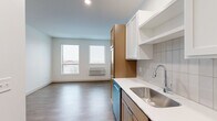 Located at 7570 32nd St N in Oakdale, Minnesota, this efficiently designed one-bedroom, one-bathroom unit offers a thoughtfully organized single-floor layout. The open-concept living and kitchen area is anchored by a well-appointed galley-style kitchen featuring warm wood-toned lower cabinetry paired with crisp white upper cabinets, white quartz countertops, a classic subway tile backsplash, and a full suite of stainless steel appliances including a range, microwave, dishwasher, and refrigerator. A deep stainless steel sink with a modern faucet completes the functional workspace. Durable wood-look plank flooring runs throughout the main living area, while natural light filters in through dual windows, brightening the open living space. A clean hallway connects the main living area to the private spaces, with sliding doors providing easy access to rooms. The bedroom offers plush carpeting underfoot, a ceiling fan with light fixture, and a spacious sliding-door closet for ample storage. The bathroom is finished with warm wood-toned cabinetry, a light countertop, a full tub-shower combination, and wood-look flooring that carries a cohesive aesthetic. Recessed lighting throughout the unit adds a polished, modern touch to this well-designed Oakdale residence.
