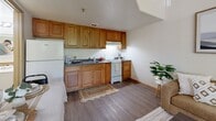Located at 5600 Boulder Hwy in Las Vegas, NV, this efficiently designed one-bedroom, one-bathroom unit offers a thoughtful single-floor layout that makes excellent use of its space. The open-concept living area features warm hardwood-style flooring, neutral walls, and a connected kitchen, creating a cohesive and functional common area. The kitchen is equipped with warm oak cabinetry, dark countertops, a white refrigerator, and a white range with ample upper and lower cabinet storage. The living space comfortably accommodates a seating area and a dining table, with an open sightline that enhances the sense of roominess. The generously sized bedroom features plush carpeting, a large window that brings in natural light with views of greenery, a sliding double-door closet offering ample storage, and vaulted ceiling details that lend a sense of openness. Framed wall art adds a decorative touch to the calm, neutral palette of the room. The bathroom is clean and well-appointed, featuring a tiled tub and shower combination with a classic accent tile border, a white vanity with countertop space, and hardwood-style flooring that ties into the rest of the unit's design.