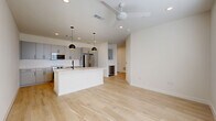Located in San Antonio's vibrant St. Mary's Street corridor, this modern 1-bedroom, 1-bathroom residence offers a thoughtfully designed single-floor layout. Light-toned hardwood flooring flows throughout the main living areas, complemented by crisp white walls and recessed lighting that create a bright, airy atmosphere. A ceiling fan adds comfort to the open-concept living and kitchen space.

The kitchen is a standout feature, showcasing sleek gray flat-front cabinetry, white quartz countertops, a white subway tile backsplash, and a full suite of stainless steel appliances including a French door refrigerator, range, and built-in microwave. A central island with an undermount sink and matte black faucet provides additional prep space and casual seating potential. A wine cooler is also integrated nearby.

The bedroom is carpeted for comfort, benefits from natural light through a window with blinds, and is equipped with a ceiling fan. It connects to a generously sized walk-in closet outfitted with extensive built-in shelving and hanging rods. The bathroom features light wood-look flooring, a white floating vanity with matte black hardware, and a tub/shower combo with dramatic floor-to-ceiling dark gray tile surround. Additional utility and storage spaces round out this efficient, well-appointed home.