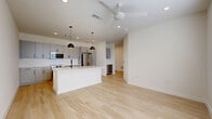 Located in San Antonio's vibrant St. Mary's Street corridor, this modern 1-bedroom, 1-bathroom residence offers a thoughtfully designed single-floor layout. Light-toned hardwood flooring flows throughout the main living areas, complemented by crisp white walls and recessed lighting that create a bright, airy atmosphere. A ceiling fan adds comfort to the open-concept living and kitchen space.

The kitchen is a standout feature, showcasing sleek gray flat-front cabinetry, white quartz countertops, a white subway tile backsplash, and a full suite of stainless steel appliances including a French door refrigerator, range, and built-in microwave. A central island with an undermount sink and matte black faucet provides additional prep space and casual seating potential. A wine cooler is also integrated nearby.

The bedroom is carpeted for comfort, benefits from natural light through a window with blinds, and is equipped with a ceiling fan. It connects to a generously sized walk-in closet outfitted with extensive built-in shelving and hanging rods. The bathroom features light wood-look flooring, a white floating vanity with matte black hardware, and a tub/shower combo with dramatic floor-to-ceiling dark gray tile surround. Additional utility and storage spaces round out this efficient, well-appointed home.