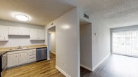 Located at 1002 Mayflower Dr in Wilmington, NC, this single-floor residence offers a functional and well-appointed layout throughout. The kitchen is a standout feature, equipped with stainless steel appliances including a refrigerator, electric range, and dishwasher, complemented by white cabinetry, granite-style countertops, and durable wood-look vinyl flooring. An overhead flush-mount light fixture brightens the space efficiently. The living and dining areas are connected by an open floor plan and are distinguished by a charming white grid-panel room divider that adds architectural character while maintaining a sense of openness. Wood-look flooring continues through these areas, and a ceiling fan provides added comfort. A sliding glass door allows natural light to filter into the living space. The bedrooms feature plush carpeting and louvered closet doors, offering a quiet and comfortable retreat. The bathroom is clean and practical, with a white vanity and mirrored medicine cabinet with overhead lighting, alongside a full tub-shower combination and wood-look flooring. Neutral wall tones and textured ceilings are consistent throughout, giving the home a cohesive and move-in ready appearance.