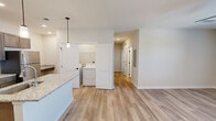 Located at 4616 Blue Diamond Way in Knoxville, TN, this well-appointed 2-bedroom, 2-bathroom single-story home offers a thoughtfully designed layout with modern finishes throughout. The kitchen serves as a central highlight, featuring rich dark-stained cabinetry, granite countertops, stainless steel appliances including a refrigerator, range, and microwave, and a center island with pendant lighting and an undermount sink. A pantry and an adjacent in-unit laundry area with a full washer and dryer add exceptional convenience. Light wood-style LVP flooring flows through the main living areas, creating a clean and cohesive aesthetic. The living room is bright and airy, with a ceiling fan and natural light from a window overlooking the surroundings. The primary bedroom is generously sized, offering plush carpeting, direct outdoor access through a glass door, and a walk-in closet with built-in shelving. The second bedroom also features soft carpeting and a window that brings in natural light. Both bathrooms are finished with granite-topped vanities, dark cabinetry, and tub-shower combinations with chrome fixtures. Two hallways and additional closets provide ample storage throughout the home, completing this functional and stylish residence.