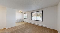 This single-floor, one-bedroom, one-bathroom unit in Marietta, WA offers a practical and comfortable layout making efficient use of its compact footprint. The living room is a welcoming space featuring warm wall-to-wall carpeting, large black-framed windows that invite ample natural light and outdoor views of surrounding greenery, a baseboard heating system, and a ceiling fan overhead — ideal for year-round comfort. The textured ceilings are consistent throughout the unit, adding a subtle architectural detail to each room.

The kitchen is positioned adjacent to the living area and is equipped with essential appliances, including a stove and refrigerator, with tile flooring that complements the cabinetry and functional layout.

The bedroom is a well-proportioned, carpeted retreat featuring a large window with blinds that provides natural light and outdoor views, along with baseboard heating. A built-in closet with a hanging rod offers convenient storage, and an electrical panel is discretely integrated into the wall.

The bathroom is clean and efficiently designed, featuring a full tub-and-shower combo with built-in wall shelving, chrome fixtures, and tile flooring. White walls and bright finishes give the space a crisp, tidy appearance. Overall, this unit provides a straightforward and functional living environment.