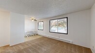 This single-floor, one-bedroom, one-bathroom unit in Marietta, WA offers a practical and comfortable layout making efficient use of its compact footprint. The living room is a welcoming space featuring warm wall-to-wall carpeting, large black-framed windows that invite ample natural light and outdoor views of surrounding greenery, a baseboard heating system, and a ceiling fan overhead — ideal for year-round comfort. The textured ceilings are consistent throughout the unit, adding a subtle architectural detail to each room.

The kitchen is positioned adjacent to the living area and is equipped with essential appliances, including a stove and refrigerator, with tile flooring that complements the cabinetry and functional layout.

The bedroom is a well-proportioned, carpeted retreat featuring a large window with blinds that provides natural light and outdoor views, along with baseboard heating. A built-in closet with a hanging rod offers convenient storage, and an electrical panel is discretely integrated into the wall.

The bathroom is clean and efficiently designed, featuring a full tub-and-shower combo with built-in wall shelving, chrome fixtures, and tile flooring. White walls and bright finishes give the space a crisp, tidy appearance. Overall, this unit provides a straightforward and functional living environment.