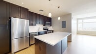 Located at 300 Alexander Ct in Philadelphia's Center City (19102), this thoughtfully designed one-bedroom, one-bathroom unit offers a contemporary urban living experience across a single, efficiently laid-out floor. Light wood flooring and a neutral color palette flow throughout, creating a bright and cohesive aesthetic.

The open-concept kitchen and living area serves as the heart of the unit. The kitchen is outfitted with rich espresso-toned cabinetry extending to the ceiling, a white subway tile backsplash, crisp white quartz countertops, and a full suite of stainless steel appliances including a refrigerator, dishwasher, microwave, and electric range. A substantial center island provides additional prep space and casual seating, while teardrop pendant lights add a modern finishing touch.

The bedroom is a well-proportioned retreat featuring multiple windows with city skyline views, filling the room with abundant natural light. Two closets provide generous storage throughout the unit.

The full bathroom is finished with neutral tile flooring, a dark-framed vanity with white countertop, a large mirror, and a tub/shower combination with white tile surround. A hallway connects the living spaces, completing this clean and modern urban residence.