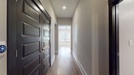 This contemporary single-story residence boasts 1310 square feet of thoughtfully designed living space. The home features two bedrooms, including a spacious 200 square foot primary suite, and three full bathrooms for added convenience. The heart of the home is an open-concept living area, seamlessly blending the kitchen and living room to create a fluid, airy atmosphere. Warm hardwood floors extend throughout, adding a touch of elegance and continuity. A notable feature is the built-in storage nook, complete with white cabinetry and a contrasting dark backsplash, offering both style and functionality. The space is illuminated by recessed lighting, enhancing the modern aesthetic. Large sliding doors with frosted glass panels provide privacy while allowing natural light to filter through. Two hallways lead to other areas of the home, ensuring easy navigation. With its clean lines, neutral palette, and thoughtful design elements, this home embodies contemporary comfort and style.