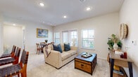 This single-floor residence features a thoughtfully designed open-concept layout that seamlessly connects the living, dining, and kitchen areas. The living room is finished with plush carpet, recessed lighting, and track lighting, with multiple windows and balcony access that invite natural light throughout. A cozy dining nook sits adjacent to the living space, framed by a large window and accented with warm, neutral tones.

The kitchen stands out with its crisp white shaker cabinetry, subway tile backsplash, and granite countertops extending across a peninsula with seating for multiple guests. Stainless steel appliances, including a refrigerator, range, and over-the-range microwave, complement the light wood-style flooring, creating a clean and functional cooking environment.

The bedroom offers a tranquil retreat with soft carpet, vaulted ceiling detail, a ceiling fan, and a window allowing natural light. It connects directly to a well-sized bathroom featuring granite countertops, white cabinetry, and a large vanity mirror. A spacious walk-in closet with built-in shelving and hanging storage provides generous organization options. The overall ambiance throughout is light, airy, and contemporary.