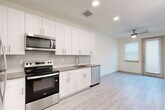 This 420 square foot apartment in Dallas, TX offers a sleek, contemporary living space. The single-floor layout maximizes efficiency, featuring an open-concept design that seamlessly integrates the kitchen and living areas. The kitchen boasts crisp white cabinetry, stainless steel appliances, and a neutral-toned countertop, creating a clean and modern aesthetic. Light wood-look flooring throughout adds warmth and continuity to the space. The bathroom is equally modern, with a tiled tub-shower combination and ample storage. Large windows and a glass door provide natural light, while ceiling fans ensure good air circulation. Recessed lighting and a neutral color palette further enhance the apartment's bright, airy feel. This well-designed space offers comfortable, low-maintenance living in a prime Dallas location, perfect for those seeking a streamlined, contemporary urban lifestyle.