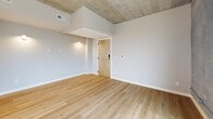 Located at 127 N 17th St in Richmond, VA, this one-bedroom, one-bathroom unit offers a compelling mix of industrial architecture and contemporary design. Throughout the space, light hardwood floors contrast beautifully with exposed concrete ceilings and raw concrete accent walls, creating a distinctly urban loft aesthetic.

The open kitchen and living area serves as the heart of the unit. The kitchen is well-appointed with white shaker cabinetry, granite countertops, a subway tile backsplash, stainless steel appliances, a range hood, and pendant lighting — all flowing seamlessly into the living area. Large windows along the exterior walls frame views of the Richmond skyline, filling the space with natural light.

The bedroom is generously proportioned and features the same hardwood flooring, exposed concrete ceiling, and raw concrete accent walls. A set of sliding closet doors reveals a built-in shelving and hanging system, offering ample storage. Wall-mounted sconce lighting adds a warm, functional touch.

The bathroom is clean and efficiently laid out, featuring white tile flooring, a full soaking tub with a subway tile surround, a granite-topped vanity with white cabinetry, and recessed lighting. The overall ambiance throughout the unit is modern and industrial, well-suited for urban living in the heart of Richmond.