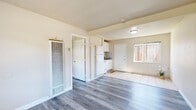 Located at 1555 164th Ave in San Leandro, CA, this single-story, one-bedroom, one-bathroom unit offers a practical and well-organized layout across a compact but efficient floor plan. The living area is bright and welcoming, featuring contemporary gray-toned laminate hardwood flooring that extends throughout the main living spaces, complemented by warm beige walls that lend a clean, neutral aesthetic. Natural light filters in through well-placed windows, enhancing the open feel of the space. The kitchen is seamlessly integrated into the main living area, outfitted with white cabinetry, a classic tile backsplash, and white appliances including a refrigerator and stove. The transition between the kitchen and entry area is marked by light-colored tile flooring. The bedroom is a comfortable, private space with its own window that brings in natural light and views of the surrounding neighborhood. Two closets provide ample storage throughout the unit. The bathroom features tile flooring, a shower-tub combination, and a clean, functional design. A dedicated entry area with a wall-mounted heater adds practical utility. The exterior dollhouse view reveals a small private outdoor space with a grassy area, offering a pleasant outdoor retreat.