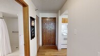 This single-floor residence offers a thoughtfully designed layout featuring one bedroom, two bathrooms, a combined kitchen and living area, and a dedicated dining space. The entryway welcomes you with warm wood-toned flooring and a wood-panel door, setting a practical yet welcoming tone throughout. The galley-style kitchen is equipped with warm honey-oak cabinetry, white appliances including a refrigerator, stove, and dishwasher, light countertops, and a stainless steel double sink — all complemented by easy-care wood-look flooring. The open living area is carpeted and bathed in natural light through a large picture window that frames views of the surrounding urban landscape. The bedroom is a comfortable retreat featuring plush carpet, a generous sliding-door closet with wood-panel doors, and a bright window. Two bathrooms serve the unit; one features a fully tiled walk-in shower with a safety grab bar and tile flooring, while the other offers an open vanity with a wide mirror, textured ceiling, and tile floors. Throughout, textured ceilings, neutral walls, and consistent finishes create a clean, cohesive aesthetic that is both functional and move-in ready.