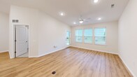 Located at 1352 Town Square Dr in Kent, Ohio, this well-appointed single-story home offers three bedrooms, two bathrooms, and a thoughtfully designed layout that maximizes everyday comfort. The entrance leads down a bright hallway with light wood-style flooring and recessed lighting, opening into a combined dining, kitchen, and living area. The kitchen is a standout feature, showcasing white shaker cabinetry, stainless steel appliances including a gas range, microwave, and French door refrigerator, a white countertop island with a built-in sink, and elegant pendant lighting overhead. The adjacent living room benefits from a ceiling fan, recessed lighting, and large windows that invite generous natural light, with a door providing direct access to the patio. The bedrooms feature plush carpet flooring and window treatments, with the primary bedroom offering a walk-in closet equipped with wire shelving. The bathrooms are finished with wood-look flooring, white vanities, and a tiled tub-shower combination. Six closets throughout the home provide ample storage. A dedicated laundry area, utility room, and an attached garage with an automatic opener round out the functional offerings of this clean, modern home.