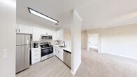 Located at 7401 W Washington Ave in Las Vegas, NV, this single-floor residence offers three bedrooms and three bathrooms within a well-designed, functional layout. The semi-open kitchen features crisp white shaker cabinetry, a tile backsplash, stainless steel appliances including a range, microwave, and dishwasher, and light wood-style flooring — all flowing seamlessly into the spacious carpeted living room. Crown molding and ceiling fans are present throughout, adding a polished finish to each room. The living room opens to a private balcony through sliding glass doors, offering outdoor views of palm trees and the surrounding landscape. The primary bedroom is generously proportioned with its own ceiling fan, direct access to a closet, and an en-suite bathroom featuring a wide white vanity with ample drawer storage. Additional bathrooms are equally well-appointed, with one offering a tub-shower combination accented by a glass block window for natural light. The dedicated laundry room houses a full-size top-loading washer and dryer beneath white overhead cabinets, providing excellent storage. Secondary bedrooms include ceiling fans and large windows that fill the rooms with natural light. Two closets and a hallway complete the thoughtfully arranged floor plan.