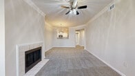 Located in Overland Park, Kansas, this single-floor residence offers a well-appointed layout designed for comfortable everyday living. The spacious living room serves as the heart of the home, featuring a tile-surround fireplace, vaulted ceilings adorned with crown molding, and a ceiling fan that enhances airflow and ambiance. Plush carpeting flows throughout the living and bedroom areas, adding warmth underfoot.

The kitchen is equipped with stainless steel appliances—including a range, microwave, and refrigerator—set against crisp white cabinetry with brushed nickel hardware and granite-style countertops. Wood-look flooring ties the kitchen together with a clean, modern aesthetic. A pass-through counter connects the kitchen to the living area, maintaining an open and social feel.

A bright, light-filled room with multiple windows and a private exterior door provides flexible space ideal for a dining room or sunroom. The bedrooms are generously sized, each featuring plush carpet and ample closet storage, with the primary suite offering direct access to an en-suite bathroom complete with a walk-in closet. Bathrooms throughout feature white cabinetry, stone-tone countertops, and wood-look flooring. A dedicated in-unit laundry area with full-size washer and dryer hookups adds everyday convenience to this thoughtfully designed home.