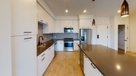 Located at 3405 Third Ave in San Diego, this well-appointed single-floor residence offers a thoughtfully designed open-concept layout that seamlessly connects the kitchen, dining, and living areas. The contemporary kitchen is a standout feature, showcasing sleek white cabinetry, dark quartz countertops, a large center island, stainless steel appliances, and a distinctive geometric tile backsplash. Warm pendant lighting adds an inviting touch to the space. Light wood-style flooring flows throughout the main living area, which opens onto a private balcony through floor-to-ceiling sliding glass doors, offering pleasant outdoor views. The bedrooms feature plush carpeting and bright windows, with at least one room enjoying expansive canyon and cityscape views. The primary bathroom is well-equipped with a dark quartz vanity, soaking tub, and a separate glass-enclosed shower with decorative tile accents, complemented by matte black fixtures. An additional full bathroom mirrors the refined finishes found throughout. A dedicated laundry area houses a full-size washer and dryer. The residence combines modern design elements with functional living spaces, making it a refined home in the heart of San Diego.