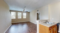 Located at 556 Merritt Morning Way in Altamonte Springs, Florida, this three-story, three-bedroom, two-bathroom residence offers a well-organized layout across its three levels. The entry level provides utility space, while the main living floor hosts an open-concept dining room, kitchen, and living room combination. Rich wood-look hardwood flooring flows throughout the main level, complemented by neutral warm-beige walls and ceiling fans that enhance air circulation. The living room features multiple windows that invite abundant natural light and views of lush tropical foliage outside. The kitchen is equipped with warm honey-toned cabinetry, light countertops, black appliances including a range and refrigerator, and a sink with ample counter workspace. A full bathroom on this level features floor-to-ceiling tile surround in a classic beige tone with a soaking tub and shower. The upper floor houses all three bedrooms, including a generously sized primary bedroom with plush carpeting, a ceiling fan, and direct access to a spacious walk-in closet fitted with wire shelving. Additional closets are distributed throughout for practical storage. A dedicated laundry room with washer and dryer hookups adds everyday convenience. With five closets total and multiple utility areas, this multi-floor residence offers functional living in a comfortable Florida setting.