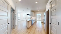 This well-appointed single-floor unit offers a thoughtfully designed open-concept layout that maximizes functionality and flow. The combined kitchen and living area serves as the heart of the space, where light wood-look flooring, crisp white walls, and recessed lighting create a bright, contemporary atmosphere. Multiple windows and a glass-paneled door invite abundant natural light, enhancing the sense of openness throughout.

The kitchen is a standout feature, outfitted with white shaker-style cabinetry, granite countertops, a herringbone tile backsplash, stainless steel appliances, and a peninsula with pendant lighting overhead. Black hardware accents provide a modern contrast against the clean white finishes.

The bedroom is generously proportioned, featuring plush carpet, large windows with exterior views, and a ceiling fan. It connects directly to a spacious walk-in closet equipped with built-in shelving and hanging rods, offering ample storage.

The bathroom is finished with granite countertops, white cabinetry, a tiled tub-shower combination, and an illuminated vanity mirror. Matte black fixtures are carried consistently throughout, lending a cohesive, modern aesthetic to the entire unit.