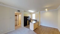Located at 825 E Palomar in Chula Vista, unit #1904 is a single-floor residence designed with functionality and comfort in mind. The open-concept layout seamlessly connects the kitchen and living area, creating a cohesive and versatile living space. The kitchen is well-appointed with cream cabinetry, a full suite of black appliances including a refrigerator, range, and microwave, and a dual-basin sink positioned beneath a bright window that allows natural light to fill the space. A central island with a laminate countertop provides additional workspace and serves as a natural dividing point between the kitchen and the adjoining living area. The living space features durable wood-look flooring, while the surrounding areas transition to plush carpeting, adding warmth and comfort underfoot. Crown molding along the ceilings adds a refined architectural detail throughout. A dedicated laundry area with side-by-side washer and dryer units is conveniently accessible from within the unit. The overall ambiance is bright and clean, with a neutral color palette that offers a versatile backdrop for a variety of interior styles.