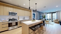 This well-appointed 2-bedroom, 2-bathroom residence at 329 Alfred Ave in Teaneck, NJ offers a thoughtfully designed single-floor layout with modern finishes throughout. Light hardwood flooring flows continuously across the open-concept living space, creating a cohesive and airy feel.

The chef's kitchen is a standout feature, showcasing light wood flat-panel cabinetry extending to the ceiling, stainless steel appliances including a gas range and French door refrigerator, a white quartz countertop, and a large center island with seating for multiple guests — all illuminated by sleek pendant lighting.

The living room opens to an outdoor balcony through floor-to-ceiling glass doors, flooding the space with natural light. Accented by a bold slate-blue feature wall, the room offers a stylish and comfortable retreat.

The spacious primary bedroom features large windows with ample natural light, a calming dual-tone color palette, and access to a generously sized walk-in closet with built-in shelving and hanging storage. The bathrooms are finished with light wood vanities, quartz countertops, large format tile flooring, and a tub-shower combination. Two dedicated closets provide excellent organization and storage throughout the home.