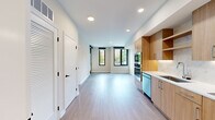Located at 3275 Washington Blvd in Arlington, Virginia, this thoughtfully designed unit offers a refined, modern living experience across a single level. The open-concept layout seamlessly connects the kitchen and living area, creating an efficient yet comfortable flow throughout the space. Light hardwood flooring runs continuously underfoot, lending warmth and cohesion to the interior.

The kitchen is a standout feature, showcasing flat-front natural wood cabinetry with under-cabinet lighting, crisp white quartz countertops, and a striking marble-look tile backsplash. Stainless steel appliances — including a built-in double wall oven, cooktop with hood, dishwasher, and refrigerator — complete this well-appointed culinary space.

Recessed lighting illuminates the main living area, which benefits from natural light through black-framed windows overlooking the surrounding neighborhood. A dedicated room features built-in wall shelving and a large window, offering flexible use as a bedroom, office, or den.

A hallway leads to additional rooms, including a space housing a stacked washer and dryer for in-unit laundry convenience. Clean white walls, black hardware accents, and minimalist finishes throughout contribute to a cohesive, contemporary aesthetic that defines this Arlington residence.