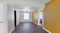 This single-floor residence offers a well-organized layout with consistent dark hardwood-style flooring throughout, creating a cohesive and grounded aesthetic across all living areas. The open living area is bright and airy, featuring neutral gray walls, a ceiling fan, and direct sightlines into the kitchen, making the space feel connected and functional.

The kitchen is a standout feature, showcasing dark gray cabinetry with sleek hardware, white countertops, a double-basin stainless steel sink, and a striking mosaic tile backsplash in a mix of gray and neutral tones. A gas range and dishwasher complete the space, which also benefits from an exterior door providing convenient access.

The bedrooms are well-proportioned, each with natural light from blinds-fitted windows set against neutral gray walls. A distinctive warm amber accent wall adds a bold design element to one of the bedrooms, which also includes a ceiling fan and a walk-in closet. An en-suite bathroom features dark espresso cabinetry, a white countertop vanity, a framed mirror, and a mosaic tile accent border. A second full bathroom includes a soaking tub with a tile surround, a window for natural light, and a matching vanity, offering practical functionality throughout the home.