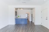 Located at 345 Heatherden Ave in Fayetteville, GA, this single-floor residence offers a clean, modern design with a cohesive aesthetic carried throughout every room. The open-concept living area is anchored by warm hardwood-style flooring and a ceiling fan, creating a comfortable and inviting atmosphere. A wide archway connects the living space to the kitchen, which stands out with its striking navy blue cabinetry and matching island with a built-in sink and light stone countertops. The kitchen is equipped with stainless steel appliances, including a range with microwave above, a refrigerator, and a classic subway tile backsplash that adds texture and character. Dark upper cabinetry provides ample storage and reinforces the bold color palette. The bedroom is generously sized, filled with natural light from multiple windows dressed with blinds, and includes a ceiling fan overhead. A barn-style sliding door adds a stylish touch to the bedroom area. The bathroom features dark vanity cabinetry with stone countertops, coordinating matte black hardware, and a tub-shower combination, all set on the same hardwood-style flooring that flows throughout the unit. Additional rooms offer versatile, open spaces well-suited for a home office or flex use. The overall design is fresh, contemporary, and move-in ready.