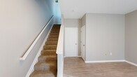 Located at 5730 Silver Falls St in Dublin, Ohio, this three-story home offers a thoughtfully designed layout spread across three levels, providing distinct zones for living, sleeping, and utility. The entry level features a carpeted staircase with a white-railed banister, light wood-style flooring, and neutral gray walls that set a clean, modern tone throughout.

The main living level hosts an open living room bathed in natural light from multiple windows dressed with blinds. The adjacent kitchen is well-equipped with white shaker cabinetry, light countertops, a white subway tile backsplash, and stainless steel appliances including a dishwasher and range. A door from the kitchen provides convenient exterior access.

The upper floor contains two bedrooms, each carpeted and generously sized, with multiple windows that invite ample natural light. The spacious primary bedroom includes a dedicated closet. Three bathrooms serve the home: one features a glass-enclosed standing shower with a white vanity and light wood-style flooring, while another offers a full soaking tub and shower combination with matching clean white finishes. Soft neutral tones, crisp white trim, and consistent flooring materials create a cohesive, move-in-ready aesthetic throughout this well-organized Dublin home.