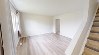 This two-storey home in Calgary, Alberta offers a practical and well-organized layout across two floors, providing comfortable living for its occupants. The main floor features a living room bathed in natural light from a large window with draping curtains, light hardwood-style flooring, and a staircase leading to the upper level. The kitchen is equipped with white cabinetry, a white electric range, a sink, and light tile flooring — offering a clean, functional space with a window allowing in natural light. The main floor also includes a hallway connecting the key areas of the home.

Upstairs, two bedrooms continue the light hardwood flooring theme, each featuring white walls and windows with curtains that invite natural light and outdoor views. The spacious primary bedroom offers ample room and a bright, airy feel. The full bathroom is finished with light tile flooring, a window for ventilation and natural light, and includes a bathtub with a shower.

Throughout the home, a consistent neutral colour palette of whites and soft beiges creates a clean, cohesive aesthetic. The combination of tile in wet areas and hardwood-style flooring in living spaces reflects a practical and modern sensibility, making this home a functional and welcoming residence.