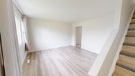 This two-storey home in Calgary, Alberta offers a practical and well-organized layout across two floors, providing comfortable living for its occupants. The main floor features a living room bathed in natural light from a large window with draping curtains, light hardwood-style flooring, and a staircase leading to the upper level. The kitchen is equipped with white cabinetry, a white electric range, a sink, and light tile flooring — offering a clean, functional space with a window allowing in natural light. The main floor also includes a hallway connecting the key areas of the home.

Upstairs, two bedrooms continue the light hardwood flooring theme, each featuring white walls and windows with curtains that invite natural light and outdoor views. The spacious primary bedroom offers ample room and a bright, airy feel. The full bathroom is finished with light tile flooring, a window for ventilation and natural light, and includes a bathtub with a shower.

Throughout the home, a consistent neutral colour palette of whites and soft beiges creates a clean, cohesive aesthetic. The combination of tile in wet areas and hardwood-style flooring in living spaces reflects a practical and modern sensibility, making this home a functional and welcoming residence.