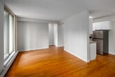 Located on the seventh floor at 111 Market St in downtown Hamilton, this one-bedroom, one-bathroom unit offers a practical and well-organized layout across a single floor. The combined kitchen and living area forms the heart of the unit, where light hardwood flooring runs throughout, contributing a warm and cohesive feel to the space.

The galley-style kitchen features white shaker cabinetry providing ample upper and lower storage, grey laminate countertops, a stainless steel double sink, and stainless steel appliances including a refrigerator and range. A textured ceiling and flush-mount lighting complete the kitchen's clean, functional aesthetic.

The living room benefits from large floor-to-ceiling sliding glass doors that open onto a private balcony, flooding the space with natural light and offering views of the surrounding downtown cityscape. A baseboard heating system runs along the exterior wall beneath the windows.

The bedroom is a well-proportioned private retreat, also featuring hardwood flooring and a window for natural light. The bathroom includes a full soaker tub with tiled surround, a single vanity with storage, and a large mirror. An entrance hallway and additional corridor provide practical transitional spaces within the unit.