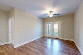Located at 1220 Pleasant Ridge Rd in Greensboro, NC, this well-appointed one-bedroom, one-bathroom unit offers a thoughtfully designed single-floor layout. The open-concept living and kitchen area serves as the heart of the space, showcasing rich hardwood-style flooring that flows throughout. The living room is bright and welcoming, featuring a ceiling fan and French doors that open to a private balcony, filling the room with natural light and providing outdoor access.

The kitchen is a standout feature, equipped with crisp white shaker cabinetry, a classic subway tile backsplash, granite countertops, and a full suite of stainless steel appliances including a range, microwave, refrigerator, and dishwasher. Elegant pendant lighting over the peninsula adds a refined touch.

The bedroom is carpeted for comfort, features a ceiling fan, and receives natural light through a window with blinds. It is complemented by a spacious walk-in closet outfitted with wire shelving for ample storage. The full bathroom includes a tub/shower combination with tiled surround and chrome fixtures. A dedicated laundry area with a full-size washer and dryer and overhead wire shelving adds everyday convenience throughout this efficiently designed unit.