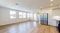 This 880-square-foot, single-story unit at 30950 Hanover Ln #05-302 in Menifee, CA offers a well-designed 2-bedroom, 2-bathroom layout. The kitchen is a standout feature, equipped with stainless steel appliances including a gas range, over-the-range microwave, dishwasher, and a full-size side-by-side refrigerator. White shaker-style cabinetry, gray quartz countertops, a subway tile backsplash, and light wood-look flooring give the kitchen a clean, modern aesthetic. The open living area continues the light hardwood flooring and features a bank of four windows that fill the space with natural light and neighborhood views. Both bedrooms are carpeted and bright, with the primary bedroom spanning 150 square feet and featuring two windows, a walk-in closet with wire shelving, and an additional closet. Both bathrooms are finished consistently with wood-look flooring, white tiled tub-shower combos with built-in shelving, gray countertops, and white cabinetry. A hallway connects all rooms efficiently, and two closets provide ample storage throughout the unit. The overall palette of neutral whites and warm wood tones creates a clean, contemporary ambiance throughout.