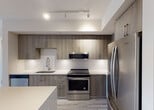 Located at 4200 NW 107 Ave in Doral, Florida, this single-floor residence showcases a clean, modern design with consistent light wood-style flooring throughout, creating a bright and cohesive aesthetic from room to room.

The kitchen is a standout feature, equipped with full-height wood-grain cabinetry in a warm grey-brown tone, stainless steel appliances including a French door refrigerator, electric range, built-in microwave, and dishwasher. A geometric patterned tile backsplash adds visual interest, while white quartz countertops provide ample workspace. Track lighting and pendant fixtures illuminate the space effectively, and an island offers additional prep and dining space.

The living and dining areas are open and airy, bathed in natural light from large black-framed windows. The neutral palette of soft whites and warm beiges lends a calm, versatile atmosphere, while a gold-toned pendant light adds a refined touch.

The bedrooms are well-proportioned, each featuring the same light flooring and large windows — one of which frames a scenic water view, adding a tranquil outdoor element to the interior experience.

The bathrooms are thoughtfully appointed. The primary bathroom includes a walk-in glass shower with white subway tile, a wood-grain vanity, and white quartz countertops. The secondary bathroom mirrors this refined style with similar finishes and a natural light window.