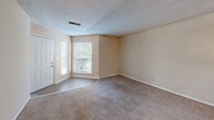 Located at 143 Stoneridge Dr in Columbia, SC, this one-bedroom, two-bathroom unit offers a practical and efficient single-floor layout. The living area greets you at the entry with a tiled foyer that transitions into wall-to-wall carpeting, creating a clear delineation between spaces. Natural light filters in through windows flanking the front door, keeping the room bright and welcoming. A textured ceiling runs throughout the unit, adding a classic touch to the neutral, warm-beige walls.

The kitchen is well-equipped with warm oak cabinetry providing ample storage, dark granite-style countertops, a double sink, and black appliances including an electric range and refrigerator. Wood-look flooring in the kitchen adds a modern contrast to the cabinetry. A hallway connects the main living areas to the bedroom and bathrooms, with additional storage accessible via interior doors.

The spacious bedroom features soft carpeting, a ceiling fan, and a sliding glass door that opens to an outdoor area, allowing for natural light and ventilation. Two bathrooms serve the unit, each featuring wood-look tile flooring, warm vanity cabinetry with dark countertops, and a full tub-shower combination with tiled surround.