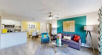 Located at 1735 Brantley Rd in Fort Myers, Florida, this single-story 2-bedroom, 2-bathroom residence offers a thoughtfully designed layout with a lively, colorful aesthetic. The open-concept living, dining, and kitchen area forms the heart of the home, bathed in natural light with wood-look flooring throughout. Bold teal and sunny yellow accent walls add personality to the shared spaces, while ceiling fans in both the living area and bedrooms provide year-round comfort. Sliding glass doors in the living room open to a private outdoor patio, extending the living space outdoors. The galley-style kitchen is well-appointed with granite countertops, white cabinetry, stainless steel appliances, a double sink, and a pantry closet. The primary bedroom continues the teal accent wall theme and features a spacious closet with louvered doors. The second bedroom is generously sized with its own walk-in closet. Both bathrooms are finished with tile surround tub-shower combinations and granite vanity countertops. Additional conveniences include a dedicated laundry area and multiple closets throughout. The overall ambiance is bright, cheerful, and functional — ideal for comfortable Florida living.