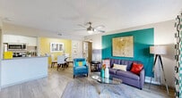 Located at 1735 Brantley Rd in Fort Myers, Florida, this single-story 2-bedroom, 2-bathroom residence offers a thoughtfully designed layout with a lively, colorful aesthetic. The open-concept living, dining, and kitchen area forms the heart of the home, bathed in natural light with wood-look flooring throughout. Bold teal and sunny yellow accent walls add personality to the shared spaces, while ceiling fans in both the living area and bedrooms provide year-round comfort. Sliding glass doors in the living room open to a private outdoor patio, extending the living space outdoors. The galley-style kitchen is well-appointed with granite countertops, white cabinetry, stainless steel appliances, a double sink, and a pantry closet. The primary bedroom continues the teal accent wall theme and features a spacious closet with louvered doors. The second bedroom is generously sized with its own walk-in closet. Both bathrooms are finished with tile surround tub-shower combinations and granite vanity countertops. Additional conveniences include a dedicated laundry area and multiple closets throughout. The overall ambiance is bright, cheerful, and functional — ideal for comfortable Florida living.