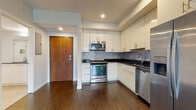 Located on Detroit Avenue in Cleveland's Ohio City neighborhood, this single-floor residence offers a thoughtfully designed layout with contemporary finishes throughout. The kitchen serves as a functional centerpiece, equipped with stainless steel appliances including a gas range, microwave, dishwasher, and a side-by-side refrigerator. White shaker-style cabinetry reaches toward the ceiling, complemented by dark countertops and a classic gray subway tile backsplash. Rich, dark hardwood flooring runs throughout the kitchen and open living area, creating a warm and cohesive aesthetic. The living space is bright and open, benefiting from a large sliding glass door that connects to an outdoor balcony and invites generous natural light. A separate bedroom features plush carpeting and a wide window with views of the surrounding neighborhood. The bathroom is finished with large-format tile flooring, a sleek white vanity with dark countertop, and a walk-in shower adorned with marble-style wall tile and a frameless sliding glass door. Recessed lighting and clean white walls throughout the unit contribute to a modern, move-in-ready atmosphere.
