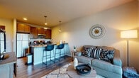 Located at 2904 Harvey St in Madison, WI, this single-floor unit offers a thoughtfully designed open-concept layout that seamlessly integrates the kitchen, dining, and living areas. The kitchen is well-equipped with stainless steel appliances, including a full-size refrigerator, electric range, and over-the-range microwave, all complemented by rich dark wood cabinetry and granite countertops. A peninsula with bar seating serves as a natural divider between the kitchen and living space, with pendant lighting adding a polished, contemporary touch overhead. Durable wood-style flooring runs throughout the main living areas, contributing to a cohesive and modern aesthetic.

The living area is comfortably scaled, featuring a sliding glass door that opens to a private balcony, allowing natural light to fill the space and offering views of the surrounding outdoor environment. The bedroom is carpeted for warmth and comfort, with a window providing additional natural light. The bathroom includes a shower-tub combination and vanity with dark wood cabinetry consistent with the kitchen's design. Overall, the unit presents a clean, modern style with functional, well-integrated living spaces.