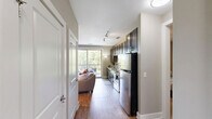 Located at 130 Sharon Township Lane in Charlotte, NC 28211, this one-bedroom, one-bathroom unit offers a thoughtfully designed single-floor layout that maximizes its compact footprint. The open-plan kitchen and living area serves as the heart of the space, where rich dark-espresso cabinetry pairs with granite countertops, a classic white subway tile backsplash, and stainless steel appliances, including a dishwasher, range, microwave, and refrigerator. Track lighting illuminates the kitchen, while hardwood flooring extends seamlessly into the living area, creating a cohesive and warm aesthetic. The living room is bright and airy, benefiting from a large sliding glass door that opens onto a private balcony offering elevated, tree-lined views of the surrounding Charlotte landscape. The bedroom features neutral taupe walls, carpet flooring, and a ceiling fan with integrated lighting, contributing to a calm and restful atmosphere. A dedicated closet provides organized storage. The bathroom is clean and functional, featuring a full tub-shower combination with brushed nickel fixtures. Overall, the unit delivers a modern, well-appointed living environment in a desirable Charlotte neighborhood.