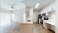 Located at 22743 Preakness Blvd in Land O' Lakes, Florida, this single-story residence offers a clean, modern aesthetic with a thoughtfully designed open-concept floor plan. The living area features soaring vaulted ceilings and wood-look plank flooring that creates a warm, cohesive feel throughout the main living spaces. A ceiling fan adds both function and comfort to the airy living room, which flows seamlessly into the kitchen via a peninsula counter with an integrated sink.

The kitchen is well-appointed with white shaker-style cabinetry, bright white countertops, and a full suite of stainless steel appliances including a refrigerator, electric range, microwave, and dishwasher. Recessed and overhead lighting keeps the space bright and functional.

The bedrooms are carpeted for comfort and feature natural light from windows with blinds. At least one bedroom includes a walk-in closet, providing generous storage. The bathrooms are finished with wood-look tile flooring, white vanity cabinetry, and white countertops. One bathroom features a sliding glass-door walk-in shower, while another includes a tub-shower combination with tiled surround. The overall palette of whites and neutrals gives the home a clean, move-in-ready appearance.