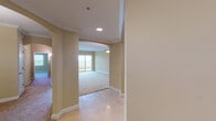 This single-floor residence combines classic architectural details with practical, well-designed living spaces. The entry area welcomes visitors with polished marble-style tile flooring that extends through the main living zones, complemented by crisp white crown molding and arched doorways that lend an air of refinement throughout.

The kitchen is a standout feature, showcasing rich warm-toned cabinetry with arched door detailing, granite countertops, and a full suite of stainless steel appliances including a French door refrigerator, electric range, and over-the-range microwave. A pass-through counter connects the kitchen to the adjacent living and dining area, which is illuminated by an elegant pendant light fixture and flows into a generously sized carpeted living room with a large sliding glass door offering natural light and outdoor views.

The carpeted bedrooms are spacious and serene, each with crown molding and ample access to closet space. The primary bathroom features a corner soaking tub with tile surround, a large vanity with warm wood cabinetry, and recessed lighting. A secondary bathroom provides a clean, functional space with matching wood vanity and tile flooring. A dedicated utility room houses the water heater and a utility sink, adding everyday convenience to this thoughtfully designed home.
