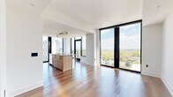 Located on Peachtree Street in Atlanta's vibrant Midtown neighborhood, this contemporary residence offers five bedrooms and three bathrooms across a single thoughtfully designed floor. The open-concept kitchen and living area serves as the heart of the home, showcasing floor-to-ceiling windows that frame breathtaking panoramic views of the Atlanta skyline and lush treetop canopy below. The kitchen features a large island with a stone countertop, warm wood lower cabinetry, crisp white upper cabinets, a subway tile backsplash, and stainless steel appliances. Rich hardwood flooring flows throughout the living areas and bedrooms, enhancing the bright, airy atmosphere. The primary bedroom benefits from expansive glazing with sweeping city views and connects to a spacious walk-in closet with built-in shelving and hanging systems. The primary bathroom is elegantly appointed with a dual-sink vanity in wood and stone finishes, a glass-enclosed shower, a soaking tub, and large-format tile flooring. Additional bathrooms include tiled tub-shower combinations. A hallway with in-unit stacked laundry adds everyday convenience. Clean white walls, modern panel doors with matte black hardware, and recessed lighting complete the sophisticated, contemporary aesthetic throughout.