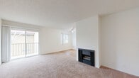 Located at 700 W Avenue I in Lancaster, CA, this one-bedroom, two-bathroom unit offers a thoughtfully laid-out single-floor plan. The bright and open living room is a standout feature, showcasing a wood-burning fireplace, soft wall-to-wall carpeting, a textured ceiling, and a ceiling fan. A sliding glass door leads to a private balcony with views of the surrounding neighborhood and mature trees. Natural light fills the space through multiple windows. The galley-style kitchen is efficiently designed with white cabinetry, dark granite-look countertops, a gas range, refrigerator, and hardwood-style flooring — maximizing functionality in a compact footprint. The spacious primary bedroom features plush carpeting, a large window with neighborhood views, and dual mirrored sliding closet doors offering generous storage. Both bathrooms are finished with hardwood-style flooring, white cabinetry, dark countertops, and tub/shower combinations with high windows for natural light and privacy. A connecting hallway links the living areas to the bedrooms and bathrooms. The exterior of the building features stucco siding with a classic red tile roof, consistent with the surrounding community's architectural style.
