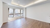 Located at 10 Dorrance Street in the heart of downtown Providence, Rhode Island, this one-bedroom, one-bathroom residence offers a thoughtfully designed layout with modern finishes throughout. The open living and kitchen area serves as the centerpiece of the unit, featuring warm hardwood-style flooring, crisp white walls, and a distinctive tray ceiling with integrated ambient lighting that adds a refined architectural touch. Large windows flood the living space with natural light while framing street-level views of the surrounding urban cityscape.

The kitchen is efficiently appointed with white shaker-style cabinetry, stainless steel appliances including a gas range, built-in microwave, and refrigerator, complemented by a clean tile backsplash and light stone countertops.

The bedroom is a well-proportioned, quiet retreat with the same hardwood-style flooring and neutral tones, and includes access to a walk-in closet for ample storage.

The bathroom is elegantly finished with classic white penny tile flooring, white subway tile walls, a walk-in shower with granite accents, a vanity with granite countertop, and wainscoting details that lend a timeless character to the space. A hallway connects the rooms, completing this well-organized and stylish urban residence.