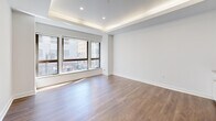 Located at 10 Dorrance Street in the heart of downtown Providence, Rhode Island, this one-bedroom, one-bathroom residence offers a thoughtfully designed layout with modern finishes throughout. The open living and kitchen area serves as the centerpiece of the unit, featuring warm hardwood-style flooring, crisp white walls, and a distinctive tray ceiling with integrated ambient lighting that adds a refined architectural touch. Large windows flood the living space with natural light while framing street-level views of the surrounding urban cityscape.

The kitchen is efficiently appointed with white shaker-style cabinetry, stainless steel appliances including a gas range, built-in microwave, and refrigerator, complemented by a clean tile backsplash and light stone countertops.

The bedroom is a well-proportioned, quiet retreat with the same hardwood-style flooring and neutral tones, and includes access to a walk-in closet for ample storage.

The bathroom is elegantly finished with classic white penny tile flooring, white subway tile walls, a walk-in shower with granite accents, a vanity with granite countertop, and wainscoting details that lend a timeless character to the space. A hallway connects the rooms, completing this well-organized and stylish urban residence.